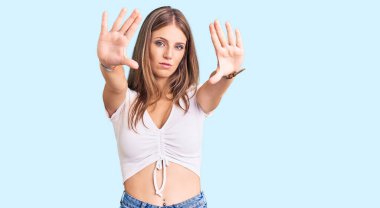 Genç, güzel, sarışın, günlük beyaz tişört giyen, el ve parmaklarıyla çerçeve yapan, kamera perspektifli bir kadın. 