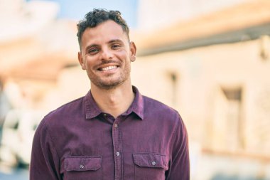 Genç İspanyol adam gülümseyerek şehirde mutlu mesut dikiliyor..