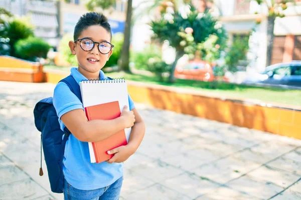 愛らしい学生少年が眼鏡をかけ街の通りで本を持っています — ストック写真