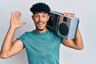 Genç Arap yakışıklı kasetçalar tutuyor, zaferi kutlayan müzikler dinliyor mutlu bir gülümsemeyle ve ellerini kaldırarak kazanan bir ifadeyle. 