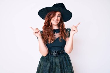 Cadı cadılar bayramı kostümü giymiş genç ve güzel bir kadın farklı yönleri işaret ederek gülümsüyor. reklam için kopyalama alanı 