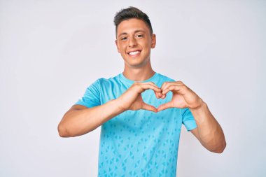 Gündelik kıyafetler giyen, aşık gülümseyen, kalp sembolü ve elleri olan genç İspanyol çocuk. romantik kavram. 