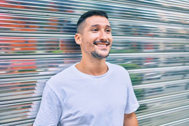 Genç İspanyol adam gülümsüyor mutlu bir şekilde şehrin duvarına yaslanıyor..