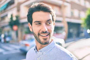 Genç İspanyol adam gülümseyerek şehirde mutlu bir şekilde yürüyor..