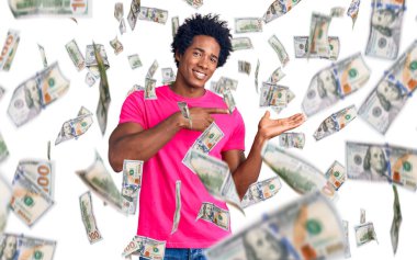 Afro saçlı, sıradan pembe tişörtlü yakışıklı Afro Amerikalı adam hayrete düşmüş ve kameraya gülümsüyor..