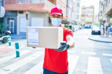 Genç teslimatçı üniforma ve koronavirüs koruma maskesi takıyor..