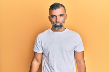 Orta yaşlı beyaz tişört giyen yakışıklı bir adam depresif ve üzüntülü, sinirli ve korkmuş bir şekilde ağlıyor. hüzünlü ifade. 