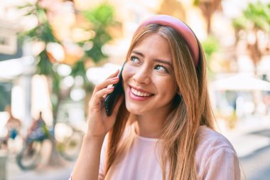 Beyaz kız gülümsüyor. Şehirdeki akıllı telefondan konuşuyor..