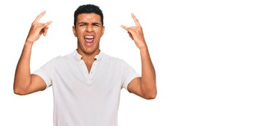 Genç Arap adam gündelik giysiler içinde çılgın bir ifadeyle bağırıyor elleri havada rock sembolü yapıyor. Müzik yıldızı. ağır müzik konsepti. 