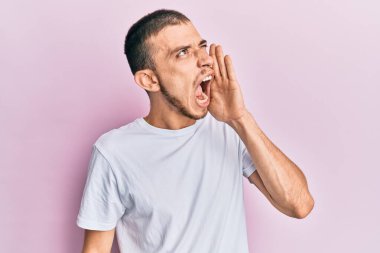 Yüzünde mutlu ve havalı bir gülümseme olan günlük beyaz tişört giyen genç bir İspanyol. şanslı kişi. 