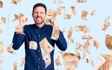 Başarı için heyecanlanan, kolları havada, gözleri kapalı ve gülümseyerek zaferi kutlayan genç, yakışıklı bir adam. Kazanan konsept.