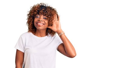 Sıradan beyaz tişörtler giyen genç Afro-Amerikalı bir kadın. Kulaktan kulağa gülümsüyor. Dedikoduları ve dedikoduları dinliyor. Sağırlık kavramı. 