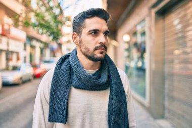 Şehirde yürüyen atkı takan ciddi bir suratı olan genç bir İspanyol..