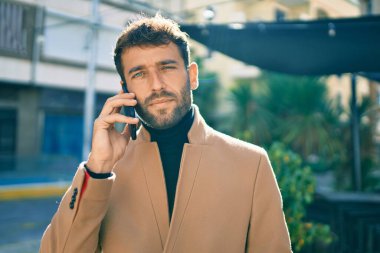 Zarif ceketli yakışıklı bir iş adamı. Açık havada akıllı telefon kullanıyor.