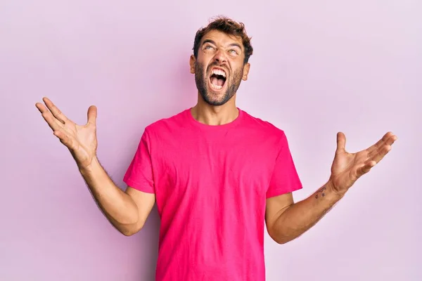 英俊的男人 留着胡子 穿着宽松的粉色T恤 背景是粉色的 疯狂的喊叫和喊叫 脸上带着咄咄逼人的表情和胳膊 沮丧的概念 — 图库照片