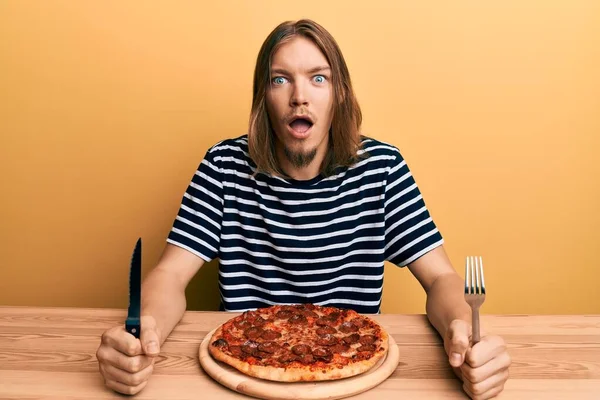 英俊的白种人 吃着美味的意大利辣披萨 惊讶的表情 兴奋的脸 — 图库照片