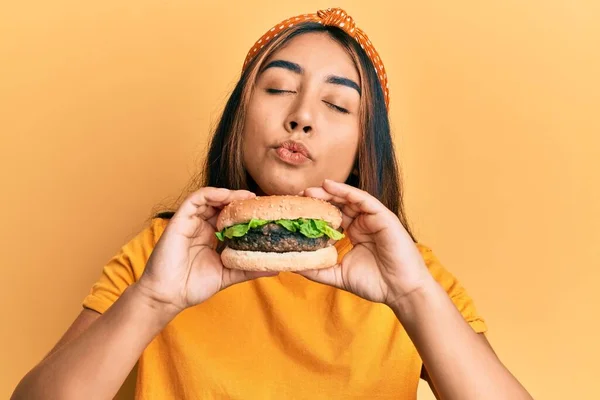 Fiatal Latin Eszik Egy Ízletes Klasszikus Burger Nézi Kamera Fúj — Stock Fotó