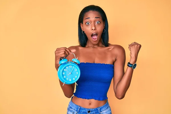 Chica Afroamericana Joven Sosteniendo Reloj Despertador Gritando Orgulloso Celebrando Victoria —  Fotos de Stock