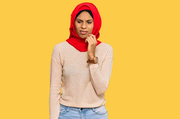 穿着传统伊斯兰头巾的年轻的非洲裔美国女人看上去很紧张 双手放在咬指甲的嘴上 焦虑问题 — 图库照片