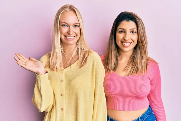 Twee Vrienden Staan Samen Roze Achtergrond Lachend Vrolijk Presenteren Wijzen — Stockfoto