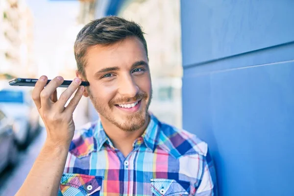 若い白人男性笑顔幸せなリスニング音声メッセージを使用してスマートフォンで市内 — ストック写真