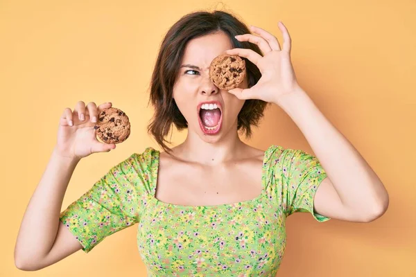 若い美しい女性が怒りと怒りで叫び フラストレーションと激怒叫び クッキーを保持 怒りと攻撃的な考え方 — ストック写真