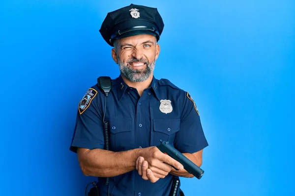 Hombre Guapo Mediana Edad Vistiendo Uniforme Policía Sosteniendo Arma Guiñando —  Fotos de Stock