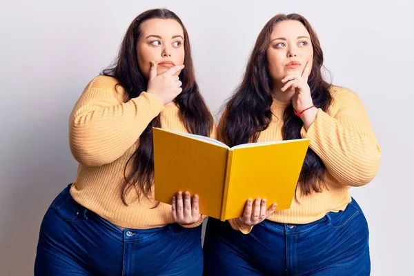 Young Size Twins Holding Book Serious Face Thinking Question Hand — Stock Photo, Image