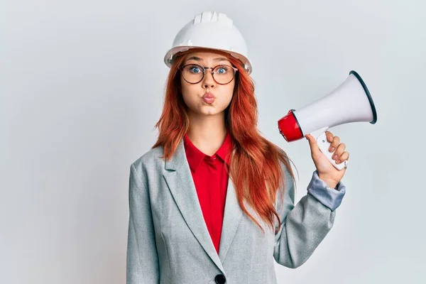 Young Redhead Woman Wearing Architect Hardhat Megaphone Puffing Cheeks Funny — Stock Photo, Image