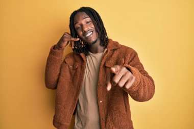 Kahverengi retro ceket giyen, gülümseyen, telefon hareketleriyle konuşan ve seni işaret eden Afro-Amerikan bir adam. Ara beni.. 
