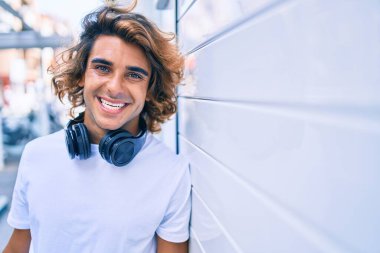 Şehrin duvarına dayanmış, kulaklık takan yakışıklı İspanyol bir adam.