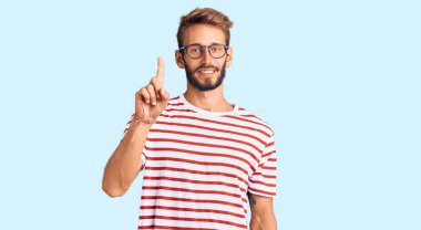 Sıradan kıyafetler ve gözlük takan sakallı yakışıklı sarışın adam başarılı bir fikirle işaret ediyor. Heyecanlı ve mutlu. Bir numara.. 