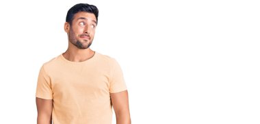 Gündelik kıyafetler giyen genç İspanyol adam gülümseyip yan tarafa bakıyor ve düşünüyor.. 