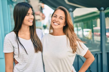 Güzel İspanyol anne ve kızı gülümseyerek şehirde mutlu mesut duruyorlar..