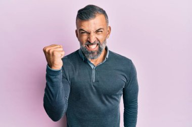 Orta yaşlı, sıradan kıyafetler giyen, sinirli ve kızgın sinirli bir adam öfkeyle bağırırken yumruğunu kaldırıyor. öfke ve agresif konsept. 