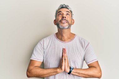 Orta yaşlı, gri saçlı, sıradan kıyafetler giyen, elleri bağlı yalvaran, dua eden, yüzünde umut ifadesi olan, duygusal ve endişeli bir adam. Yalvarıyor. 