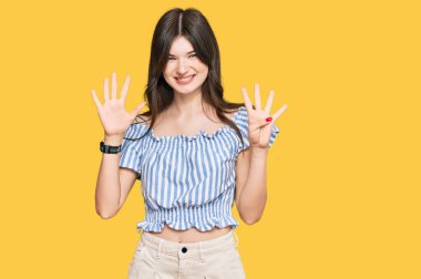 Genç, güzel, beyaz, günlük kıyafetler giyen, dokuz numaralı parmaklarıyla işaret eden, kendinden emin ve mutlu bir kız.. 