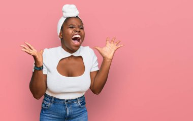 Young african woman with turban wearing hair turban over isolated background celebrating mad and crazy for success with arms raised and closed eyes screaming excited. winner concept  clipart