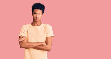 Gündelik kıyafetler giyen, kuşkucu ve gergin genç Afro-Amerikalı bir adam. Yüzünde çapraz kollarla onaylamayan bir ifade var. negatif kişi. 