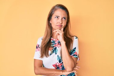 Orta yaşlı İspanyol bir kadın, sıradan bir çiçekli elbise giyiyor ciddi bir yüz, eli çenesinde soruyu düşünüyor, kafa karıştırıcı bir fikir. 