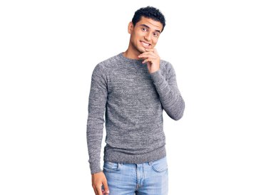 Gündelik kazak giyen İspanyol yakışıklı genç adam kameraya bakıyor kollarını kavuşturup gülümseyerek ve çenesini kaldırarak. Olumlu düşünmek. 