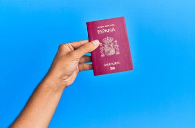 İspanyol pasaportlu bir adamın elleri mavi arka planda..