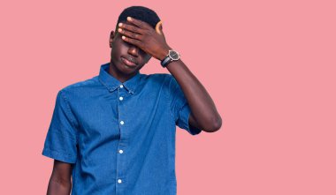 Genç, Afro-Amerikan bir adam, günlük kıyafetler giyip, elleriyle gözlerini kapatıyor, ciddi ve üzgün görünüyor. Görme, saklama ve reddetme konsepti 