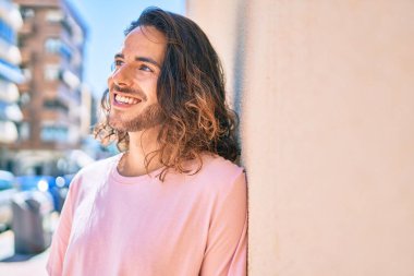 Genç İspanyol adam gülümsüyor. Mutlulukla duvara bakıyor.