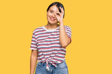 Kısa saçlı, sıradan kıyafetler giyen, el hareketleriyle gülümseyen, mutlu yüzüyle parmaklarının arasından bakan güzel bir genç kadın.. 