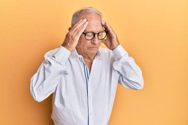 Kafkasyalı kıdemli bir adam günlük kıyafetler giyiyor ve kafasında el olan gözlükler var. Stres yüzünden başı ağrıyor. migren ağrısı. 