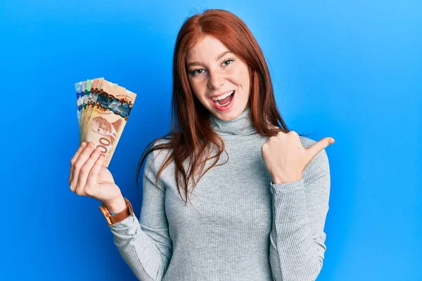 Kanadalı Dolarları Tutan Genç Kızıl Saçlı Kız Başparmağını Yukarı Kaldırıyor — Stok fotoğraf