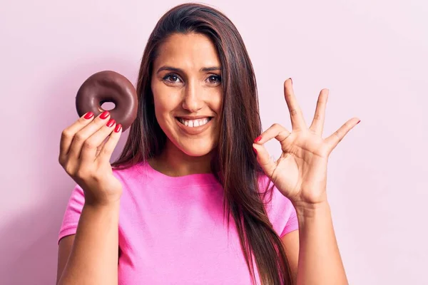 Joven Hermosa Morena Sosteniendo Donut Chocolate Haciendo Signo Con Los — Foto de Stock