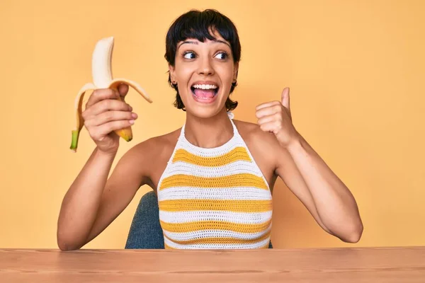 Morena Adolescente Comiendo Plátano Como Bocadillo Saludable Apuntando Pulgar Hacia —  Fotos de Stock