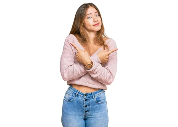 美しいですブロンド女性身に着けていますカジュアル冬ピンクセーター指で両側を指しています 異なる方向の同意 — ストック写真